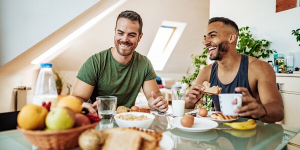 Gay couple having healthy breakfast in cozy bed and breakfast