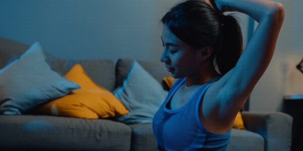 Young Asia lady in sportswear doing yoga exercise working out in living room at home at night.
