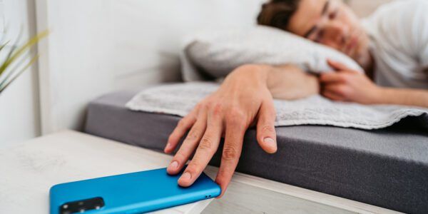 Young Man Snoozing Alarm On A Smart Phone