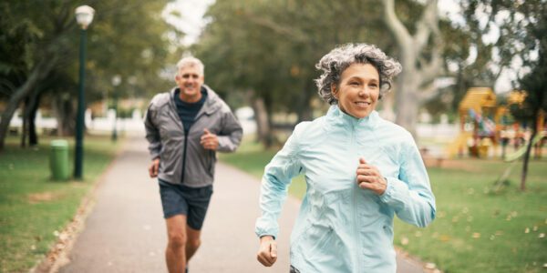 An older couple jogs in the park.