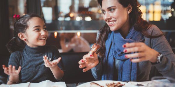 A mother and daughter enjoy a meal of chicken wings together.