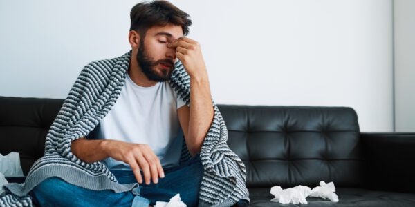 Man suffering sinusitis sitting on couch at home having headache